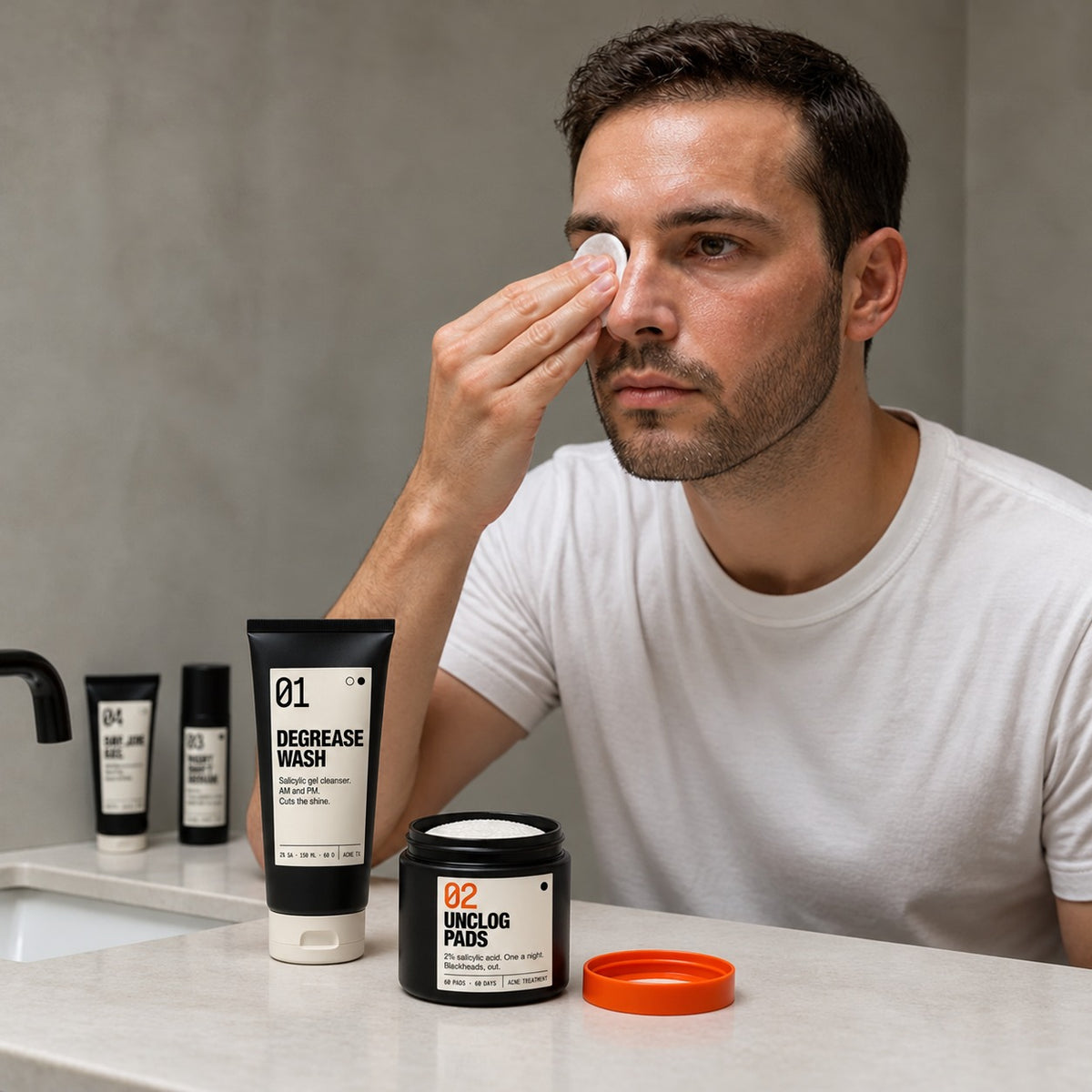 Man at the mirror with an Unclog Pad; Degrease Wash and Pads on the counter